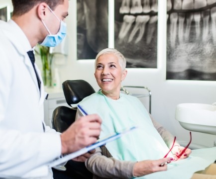 Dentist and patient discussing the cost of dental implant tooth replacement