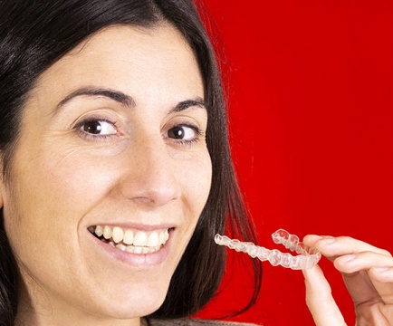 Woman smiling holding Invisalign in Baltimore