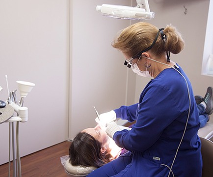 Dental team member performing dental checkup and teeth cleaning