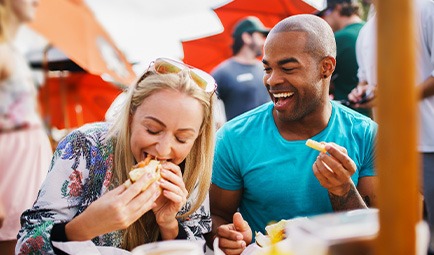 Two friends smiling while eating lunch outside