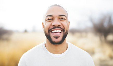 Man in white shirt smiling outside